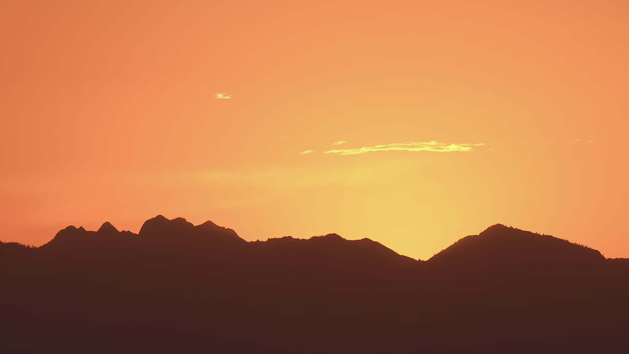 산맥의 실루 위에 해가 지면 생생한 하늘