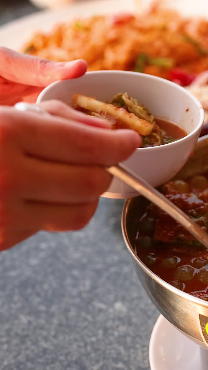 A hand serves soup from a hot pot
