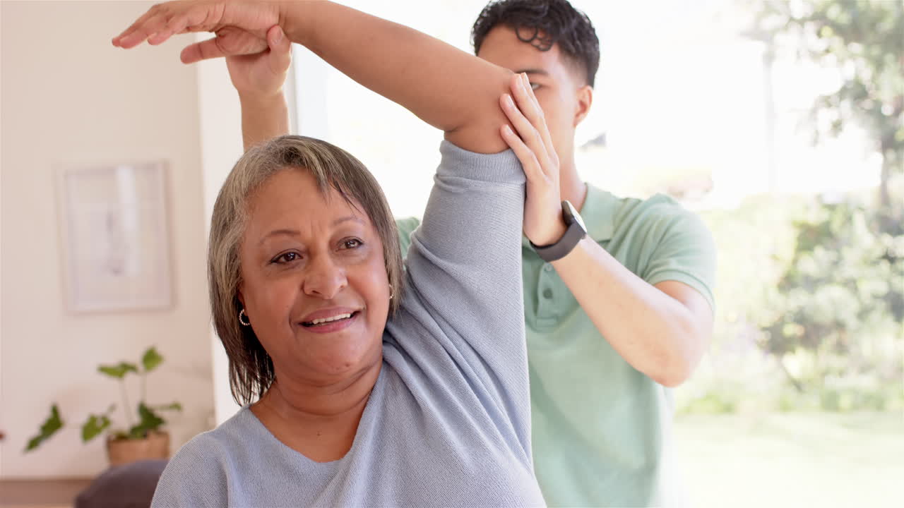 Physiotherapist assisting senior woman with arm stretching exercise in clinic