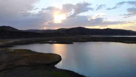 aerial drone fly in over dried-up irvine lake in southern california at beautiful sunset- lake is almost empty due to drought