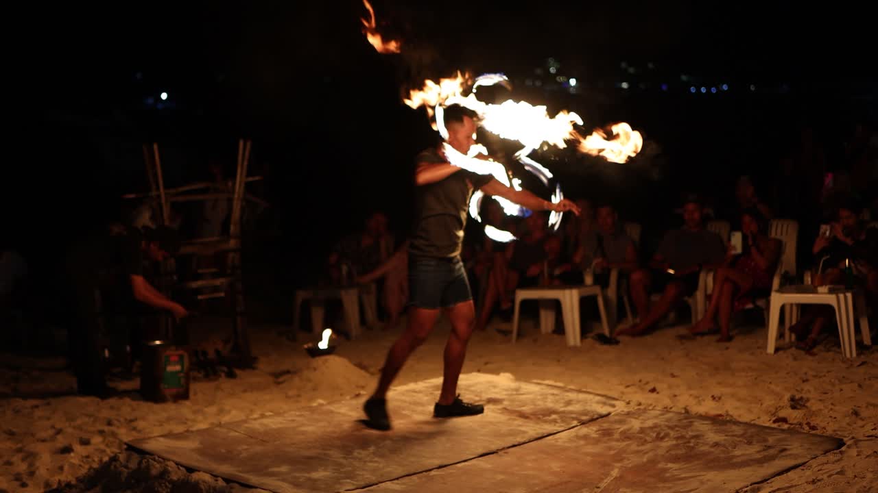 Man performing fire twirling beach in front of audience