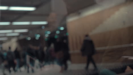gente en la estación de metro vista a través de la ventana del tren