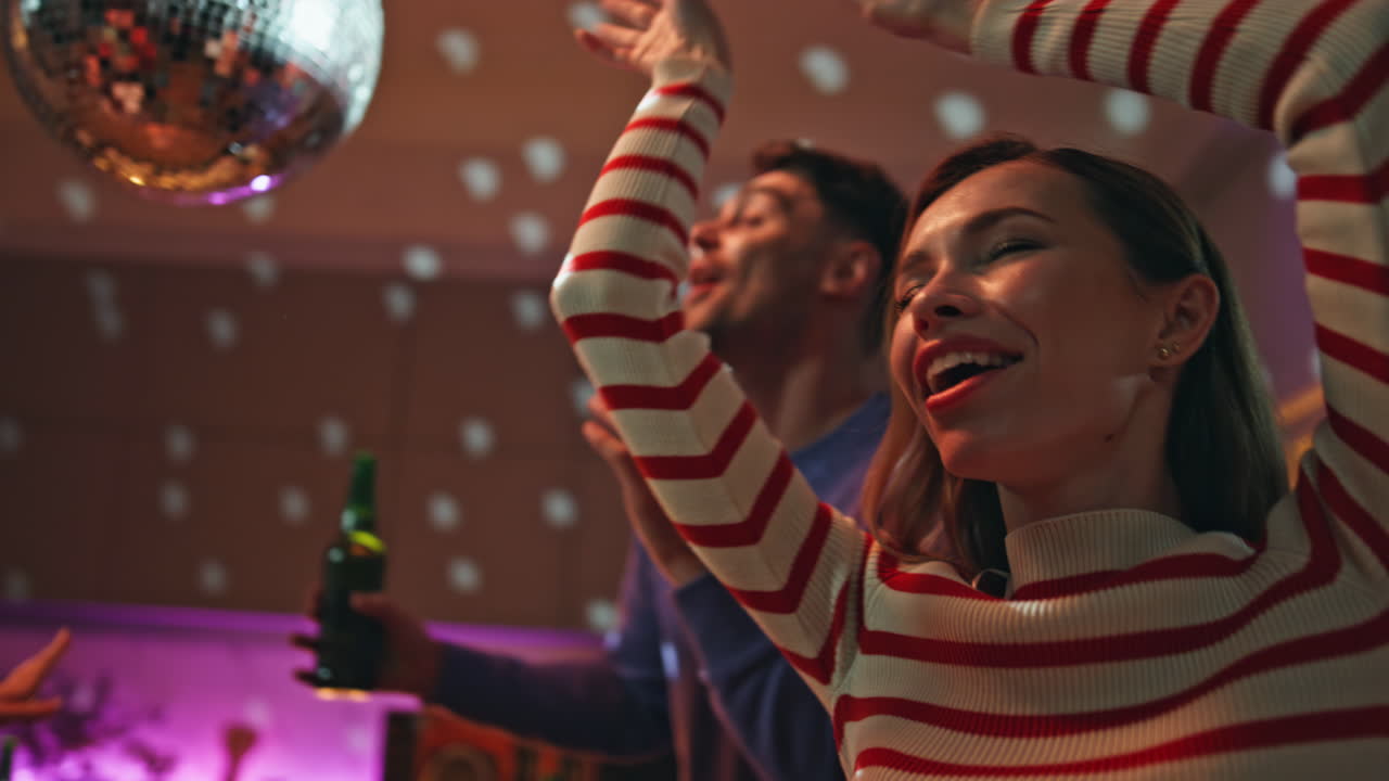 Carefree millennials dancing disco party under light ball close up. People fun