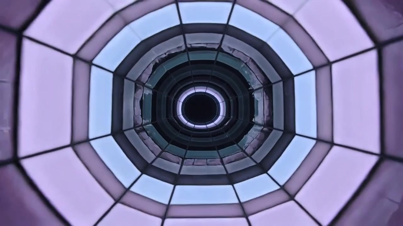 Zeigt ein achteckiges Oberlicht mit wechselnden LEDs im Atrium, das segmentierte Paneele, radiale Rippen und eine zentrale Leere enthüllt.