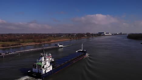 empty cargo ships sailing across the river of oude maas in south holland, netherlands on a sunny day. drone orbit