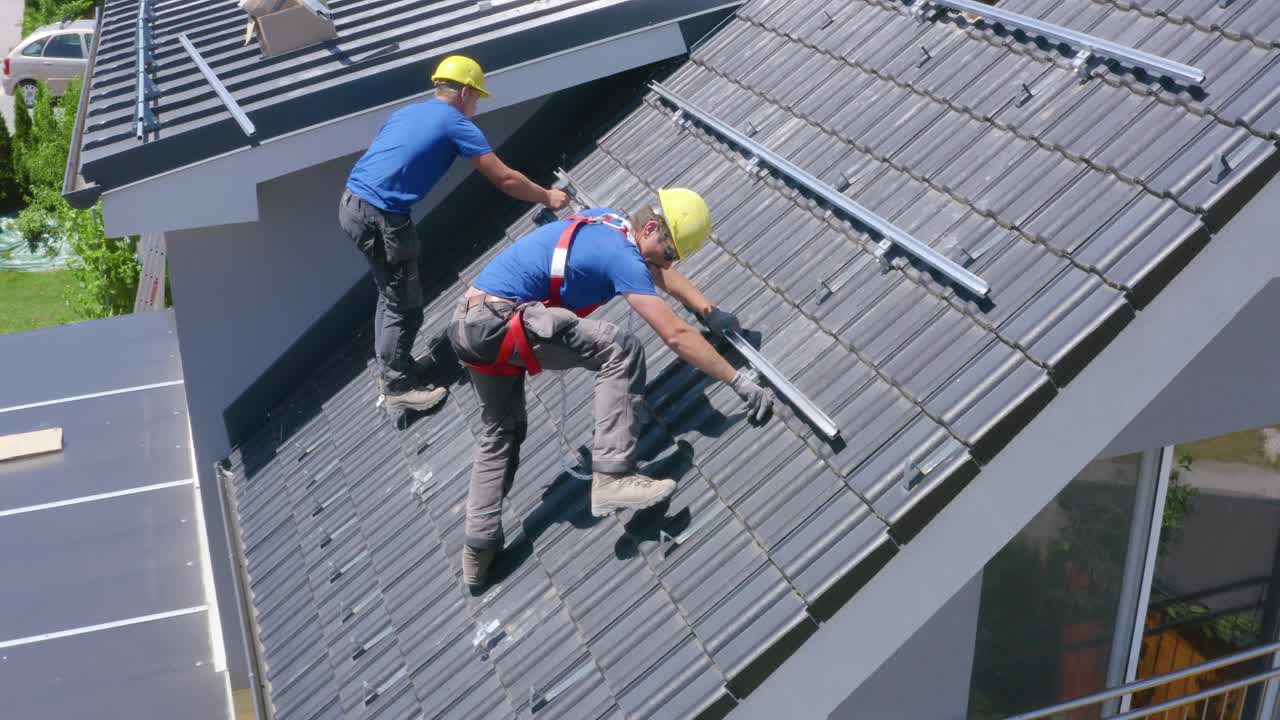 Tradesman Working Together To Install Solar Panels On Roof Of House