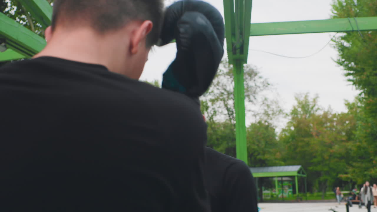 L'istruttore spiega le tattiche all'aperto, il giovane coach fornisce strategie di box sotto un padiglione verde, istruzioni sulle tattiche fornite dal giovane coach al partner all'aperto con vivo contatto visivo