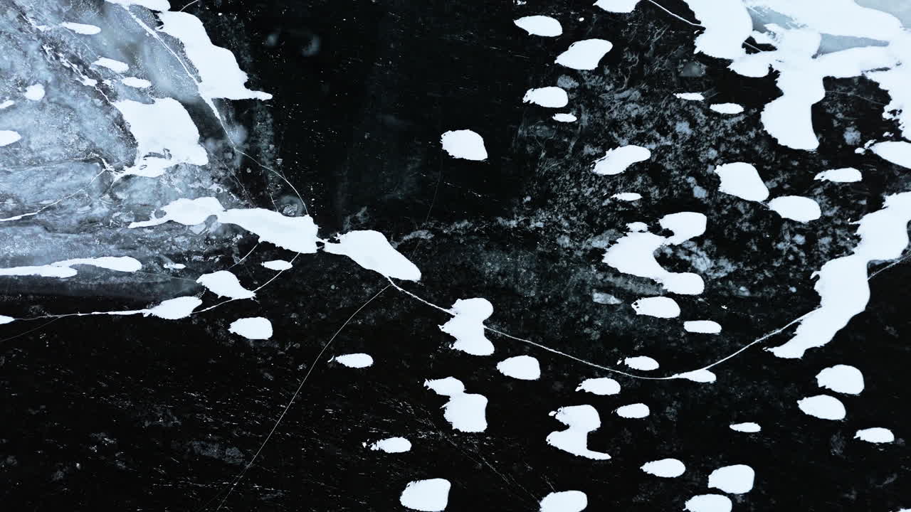 Frozen fjord ice with cracks and snow patches in Tromsø, Norway, aerial view