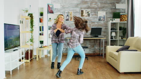 cheerful mother and daughter dancing in living room