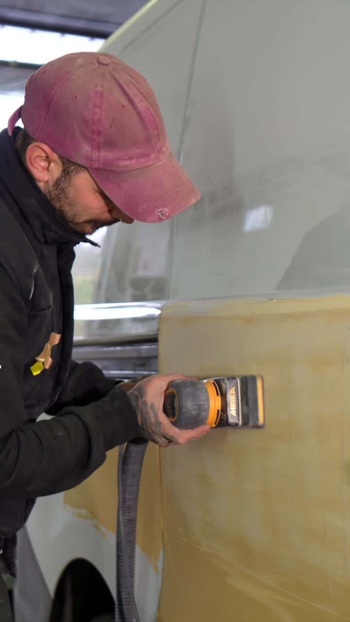 Man Sanding Vehicle Bodywork in an Auto Repair Shop