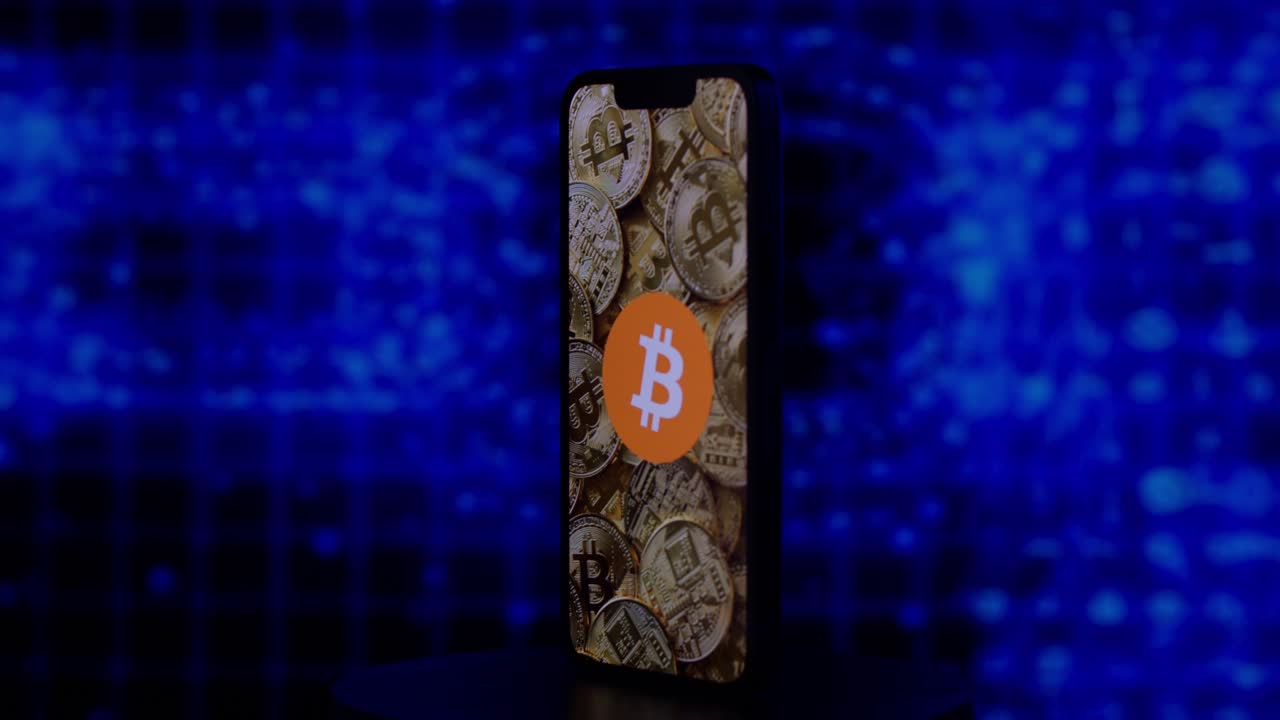 logotipo de bitcoin encima de bitcoins en un iphone con fondo de cadena de bloques