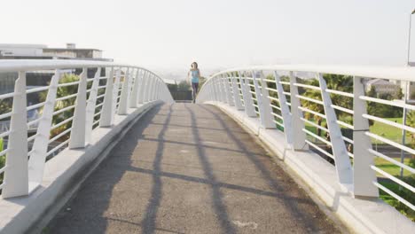 mujer joven corriendo por un puente