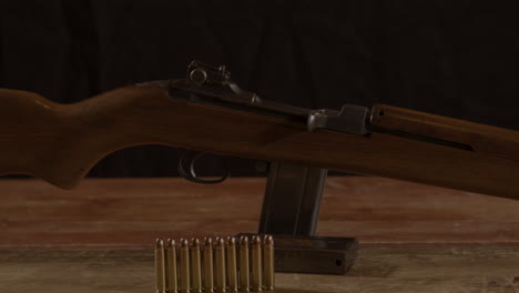 dolly of classic 30m1 carbine rifle with ammunition on the foreground standing on a wooden surface