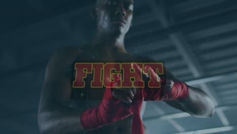 animation of fight text against young african man wrapping hand with sports bandage at gym