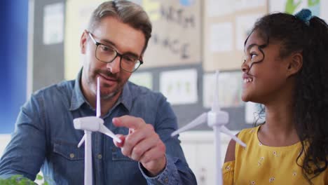 un maestro y una estudiante diversos, aprendiendo sobre la energía eólica y las fuentes renovables de energía