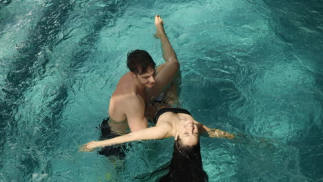 una pareja feliz divirtiéndose en la piscina.