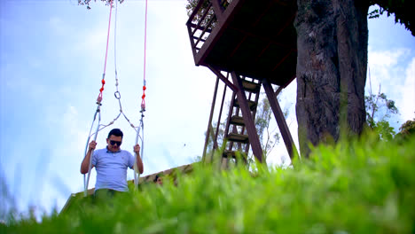 Ground-view-of-man-in-sunglasses-at-famous-swing-in-Baños,-Ecuador