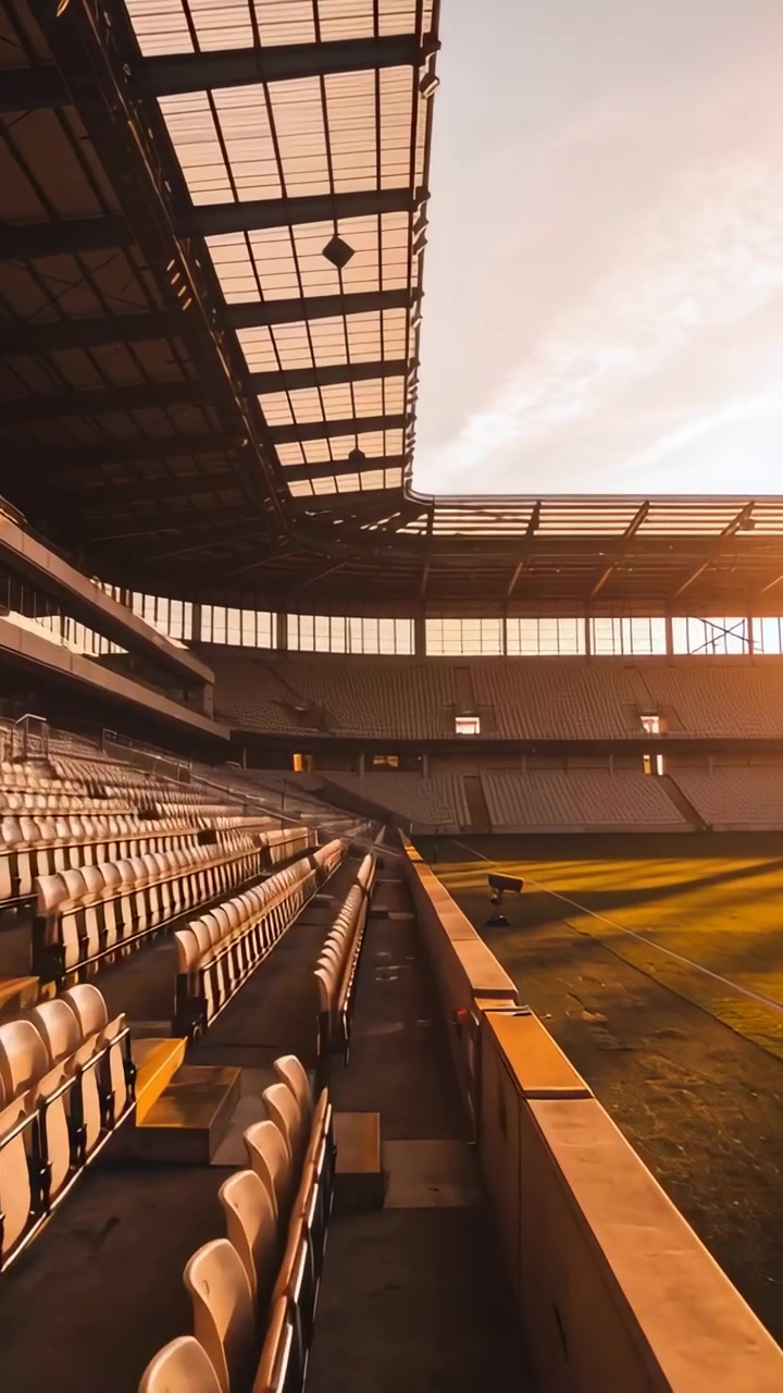 Vertical video: Moving camera revealing empty tiered seats, barrier and cart at stadium, copy space