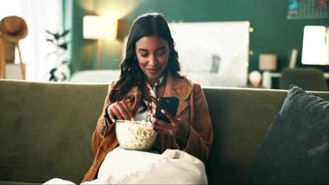 woman relaxing on couch with popcorn and phone