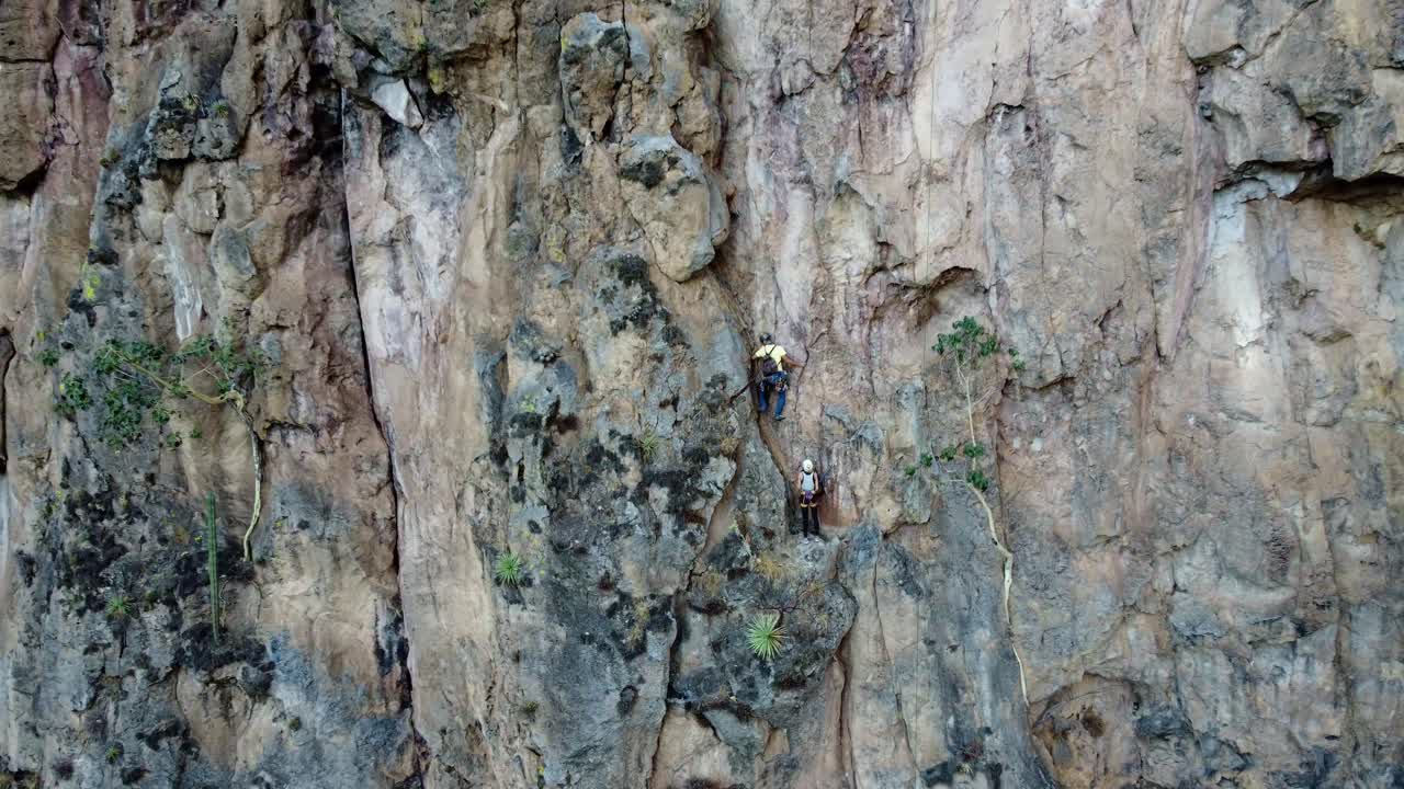 Two Climbers Scaling a Dramatic Cliff Face