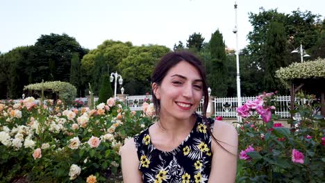 slow motion:beautiful woman smiles at camera while sitting in the park