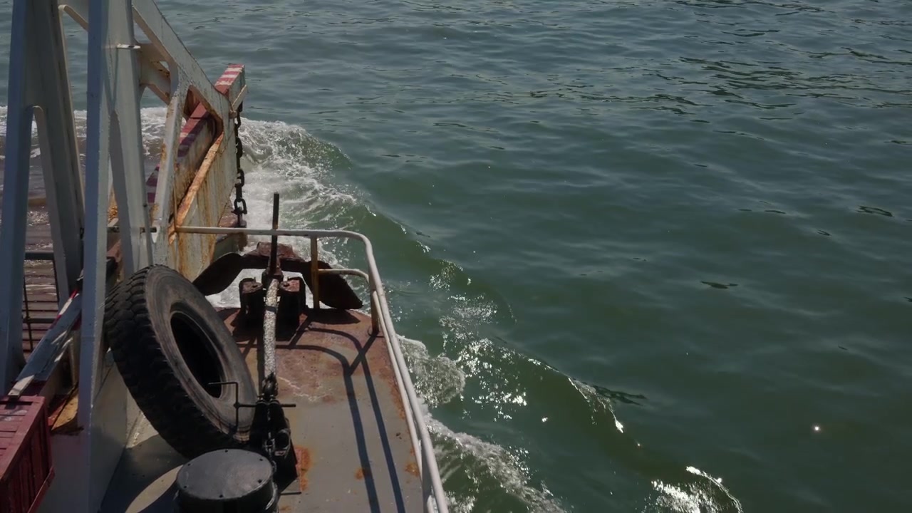 Ha Long, Quang Ninh, Vietnam. Cubierta lateral de ferry con defensa de neumático y barandillas, mientras las olas dejan una estela junto a la embarcación en movimiento a través de las aguas de la bahía. Toma en picado.