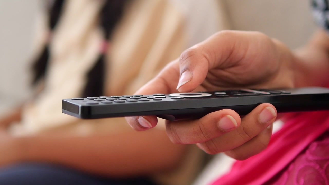 Primo piano di una persona che tiene un telecomando TV