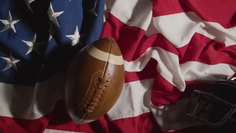 fotografía cenital de una persona arrojando fútbol americano sobre la bandera de rayas y estrellas con casco