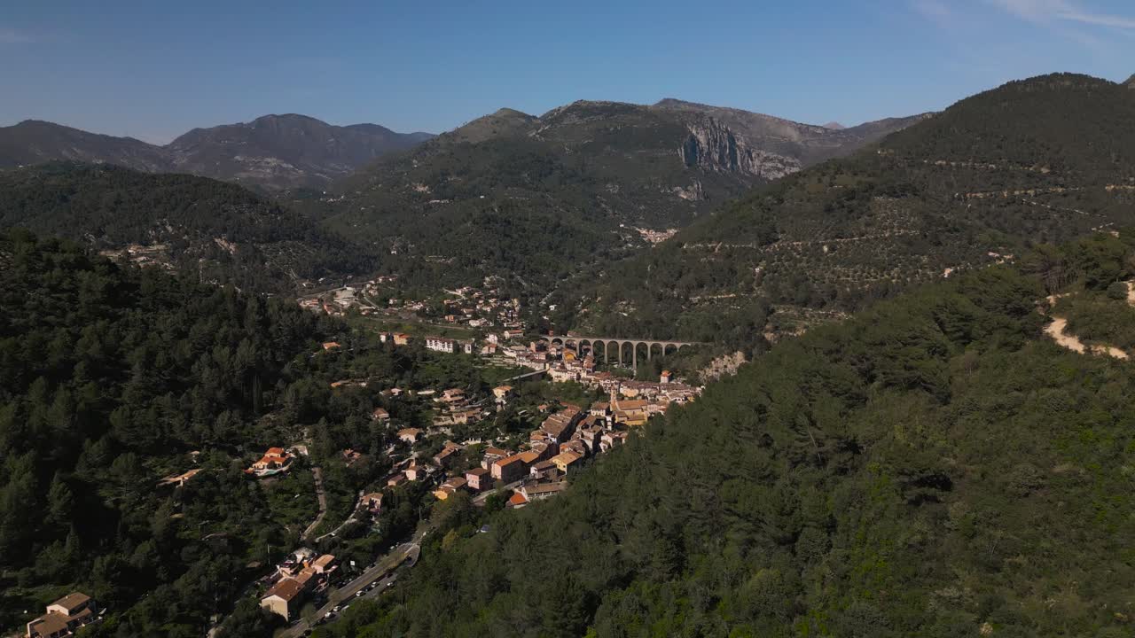 un pintoresco pueblo enclavado en los exuberantes bosques de la riviera francesa, bajo cielos despejados, vista aérea