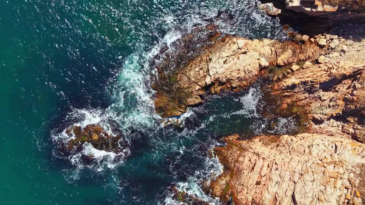 Onde si infrangono contro coste rocciose sull'oceano durante il giorno.