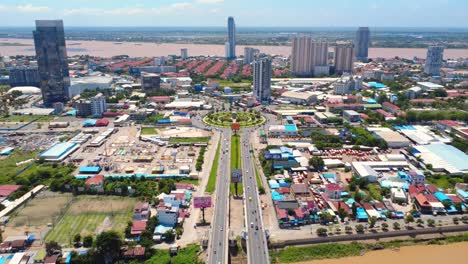 drone video capturing vibrant chroy changvar cityscape with bustling roundabout, modern skyscrapers, and serene riverside under clear blue skies in phnom penh.