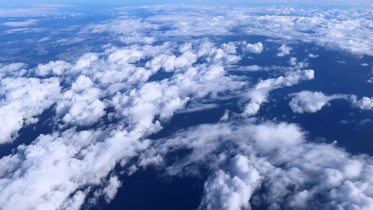 Nuvole bianche fluttuano su un oceano blu profondo visto dall'alto, creando una vista pacifica.