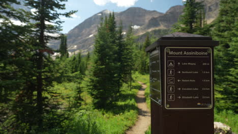 Young-Woman-on-Hiking-Trail-Passing-Sign-With-Directions