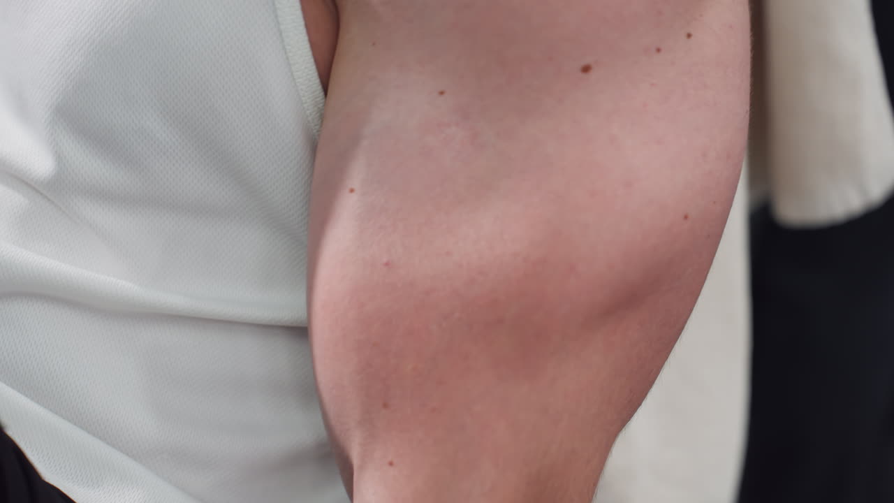 Gym enthusiast arm pushing elliptical trainer handle with focused form in bright modern gym under intense lighting muscles straining sweat shining on skin details highlighting fitness motion energy