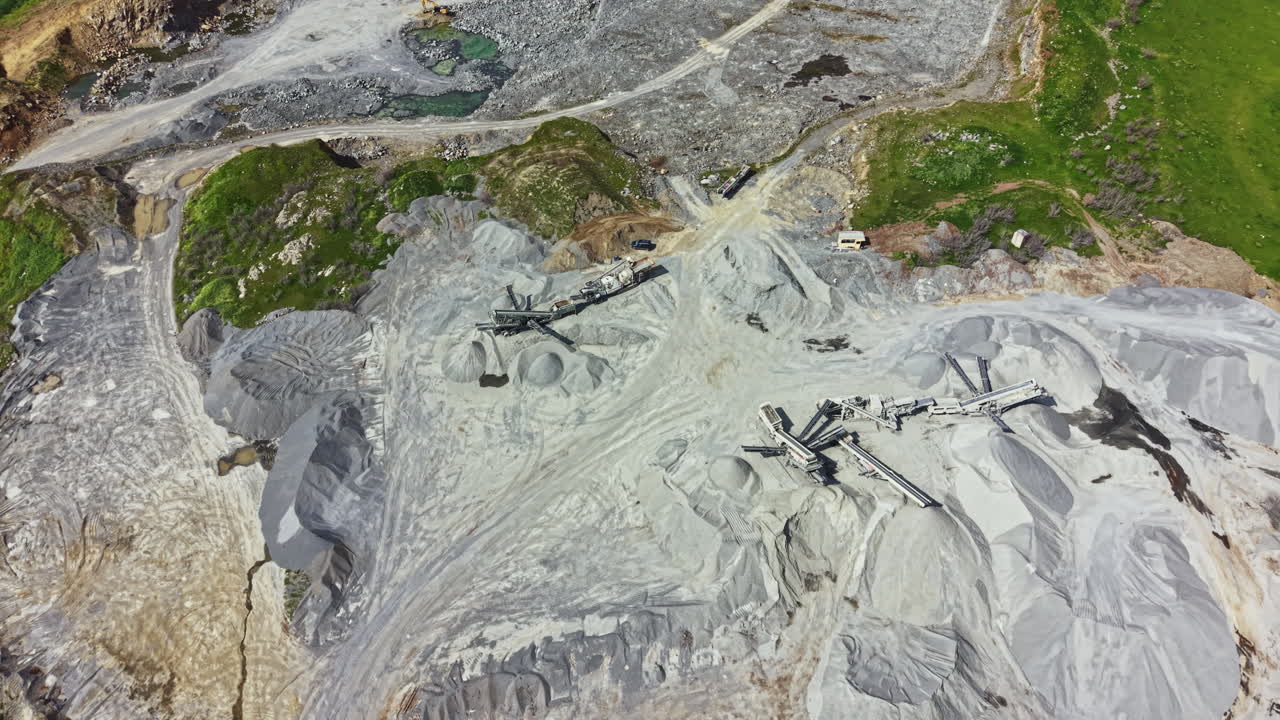 Granitbrud med tungt maskineri og råt stenmateriale under udvinding og forarbejdning på et bjergsted.