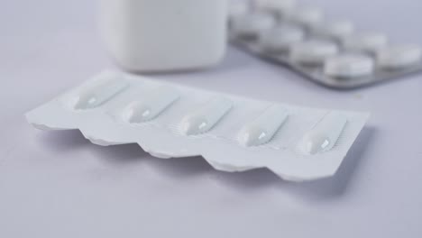 primo piano di suppositorie e pillole su sfondo bianco