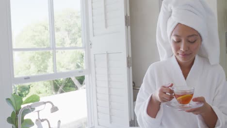 Happy-asian-woman-drinking-tea-in-bathroom,-in-slow-motion