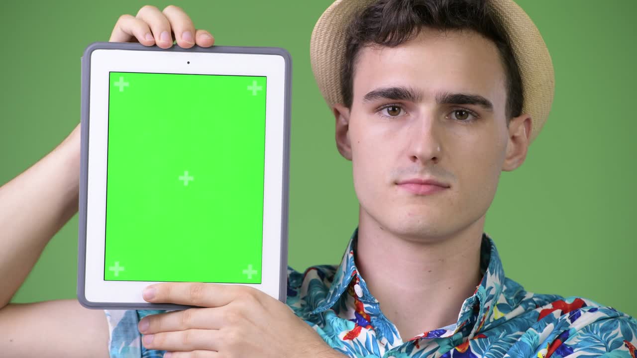 Young handsome tourist man showing digital tablet