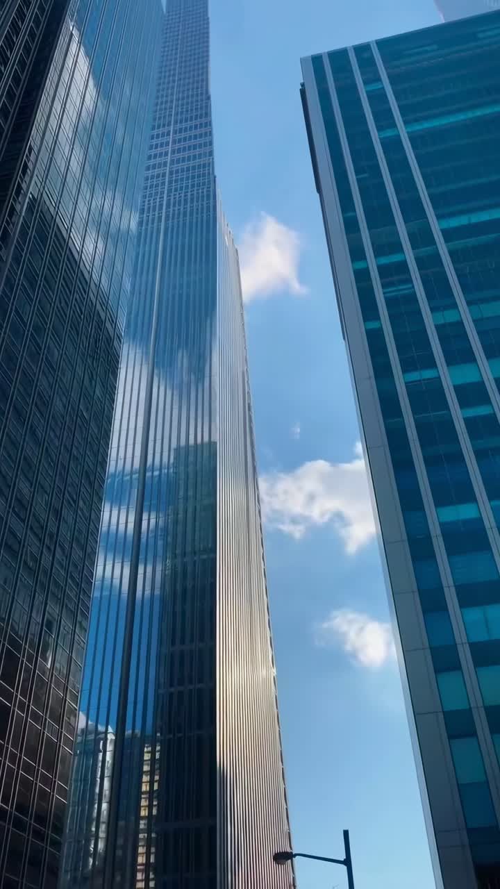 O vídeo captura uma vista em ângulo baixo de arranha-céus modernos, destacando a arquitetura elegante.