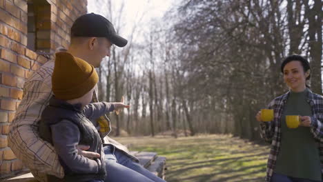 Caucasian-couple-and-their-son-drinking-tea-outside-a-country-house