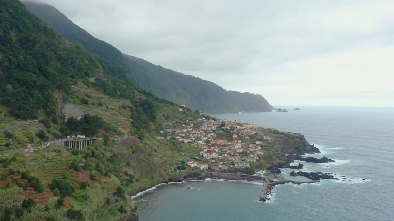 Costa di Seixal, Madeira, con onde e montagne tra le nuvole. Orizzonte oceanico panoramico con scogliere e cielo, ripresa aerea panoramica in ascesa.