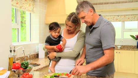 cute little boy eating a sweet red peper while his father is cooking vegetables