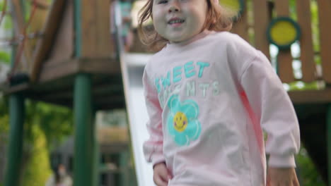 young korean-ukrainian girl goes down park slide jumps up joyfully