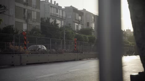 una calle en tel aviv con cercas de construcción durante una puesta de sol de verano