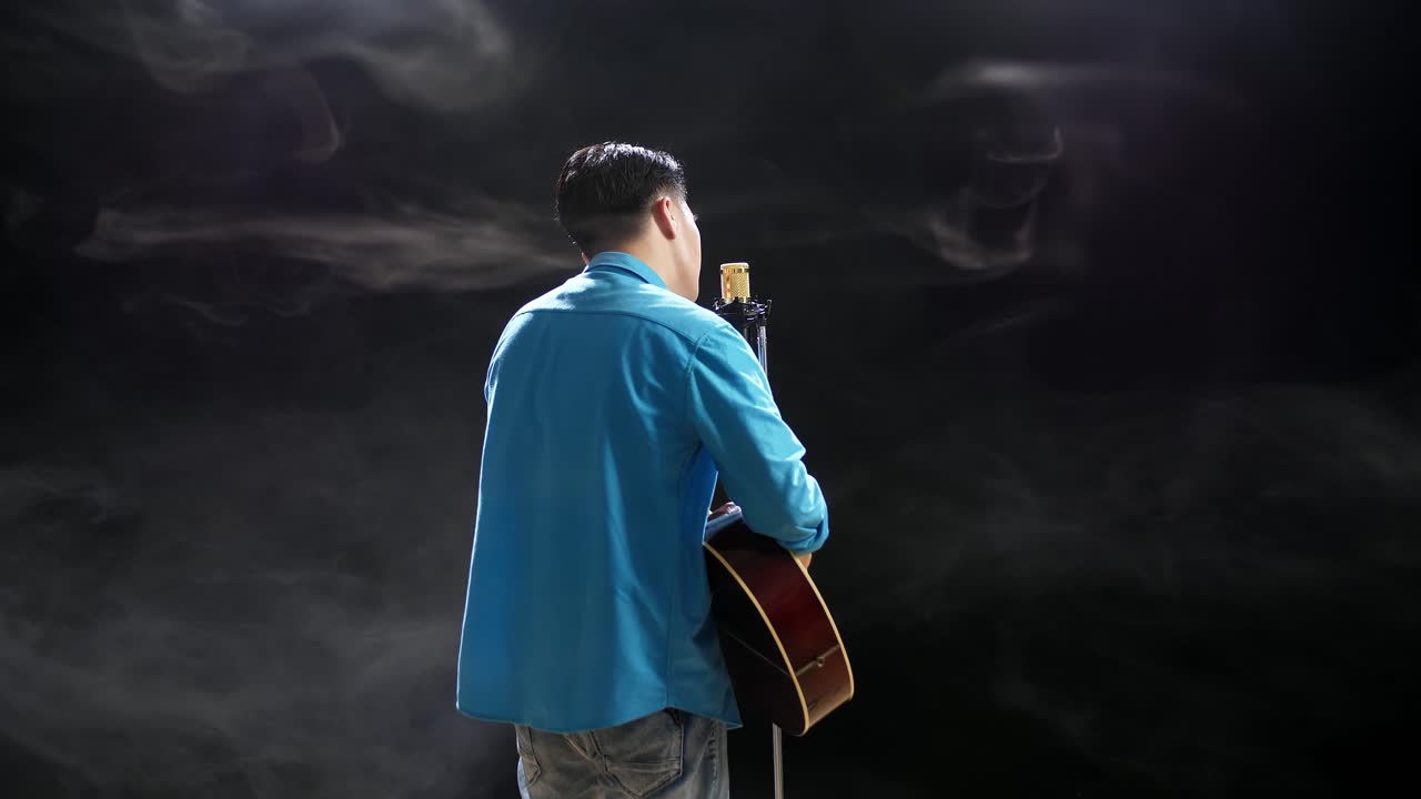 무대에서 어쿠스틱 기타를 연주하는 남자