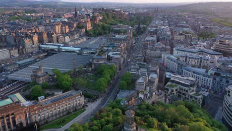 Vista-Aérea-Del-Paisaje-Urbano-Del-Drone-De-La-Estación-De-Tren-Del-Centro-De-La-Ciudad-De-Edimburgo-En-La-Hora-Dorada,-Bajando,-Escocia