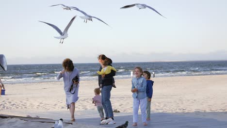 family with children feed huge amount of gulls birds in sky flying over her head