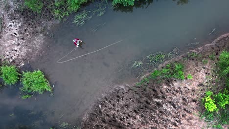 el pescador se para en el río estrecho y lanza la mosca con la caña de pescar