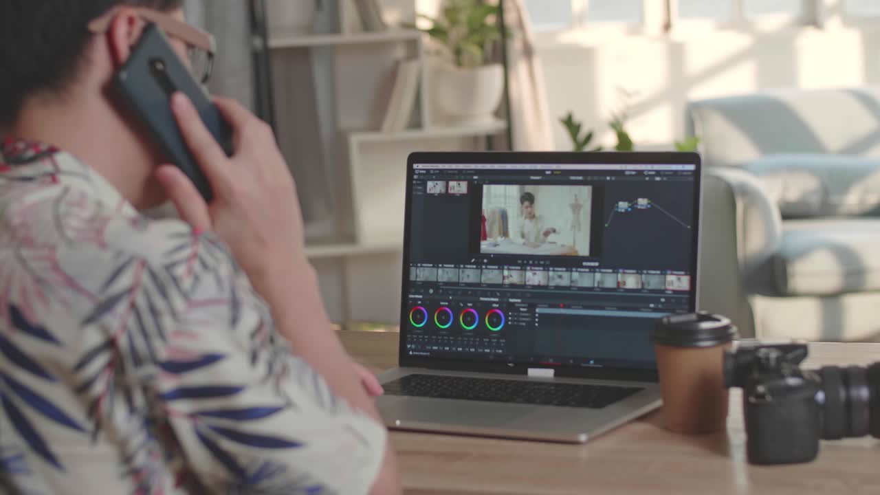 Man Editor Talking On Mobile Phone With Video Editing App / Software On His Laptop Computer