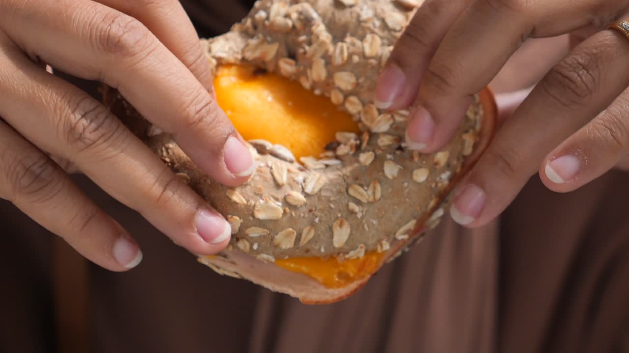 Donna che mangia un panino al formaggio e prosciutto